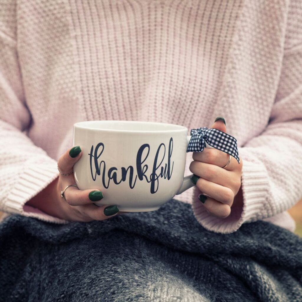 woman holding white mug that says thankful in black 