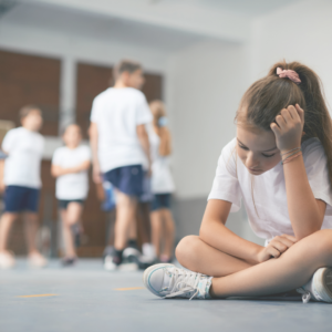 ADHD child struggling at school and looking sad while peers are standing behind her talking